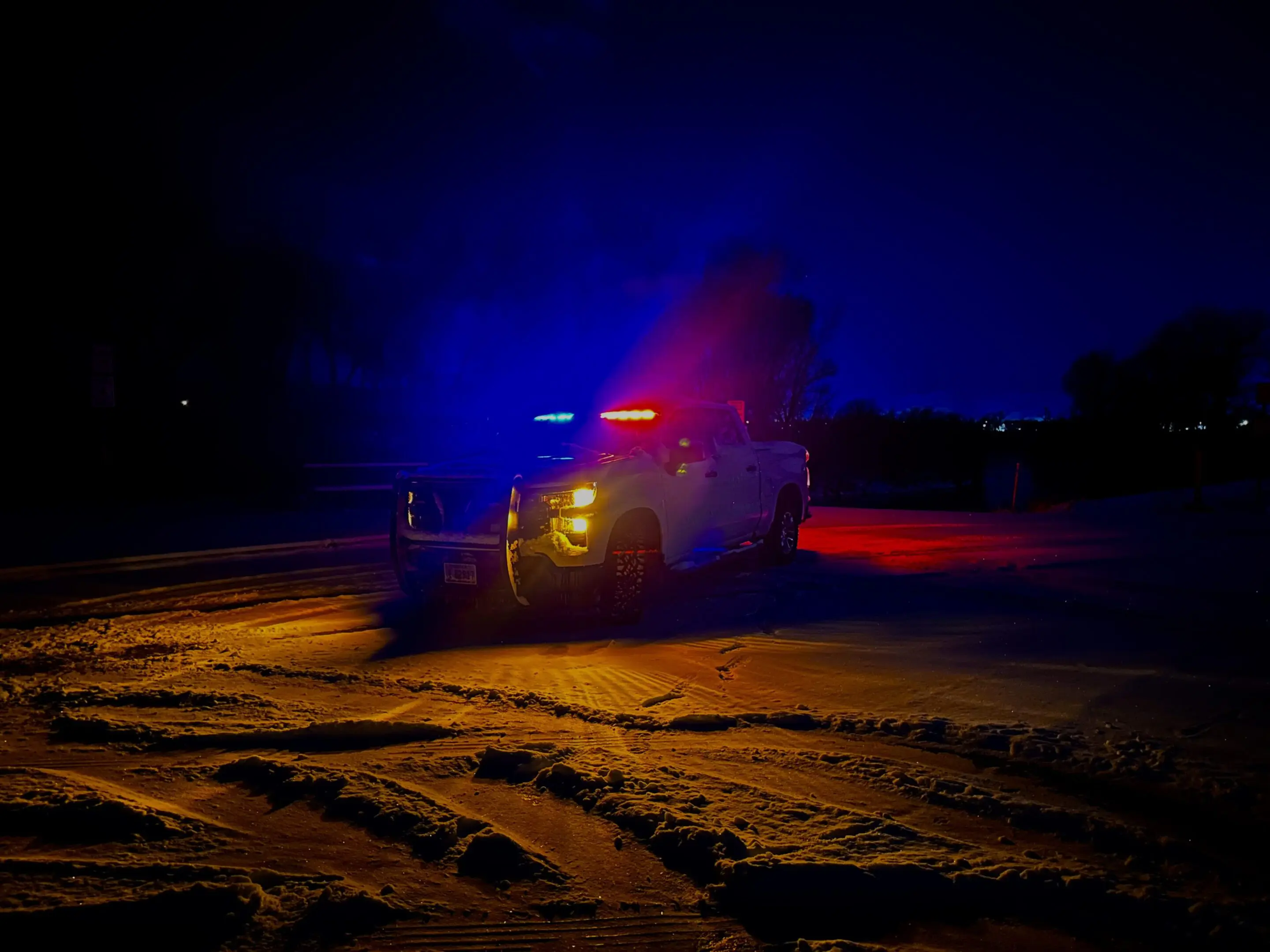 A truck is driving down the road at night.